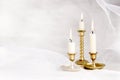 Burning candles in vintage metal candlesticks on white abstract white tulle material  background. Royalty Free Stock Photo