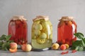 Three canned apple and cherry compote in large glass jars on gray table.