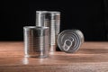 Three canned goods of different sizes in aluminum on a black background