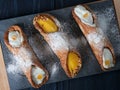 Three cannoli pastries on a slate, set on a dark blue wooden board Royalty Free Stock Photo