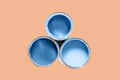 Three cans filled paint of classic blue color isolated on Peach Quartz trendy color background