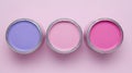 three cans of paint on a pink background, three of which are different colors of paint, the third one is pink and the third one