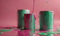 Three cans of paint are sitting on a pink background, with one of them being green and the other two being pink and gree Royalty Free Stock Photo