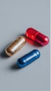 Three colorful capsules rest on a neutral surface, including golden, red, and blue Royalty Free Stock Photo