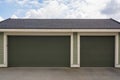 Three car garage with wide door on cloudy sky background