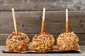 Three caramel apples with nuts against rustic wood Royalty Free Stock Photo