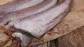 Three carcasses of fresh-frozen hake fish on a paper
