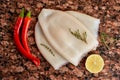 Three carcasses of fresh raw squid with lemon, pepper, thyme on a marble stone dark table