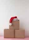 Three cardboard boxes are stacked one on top of the other there is a red Santa Claus hat on top