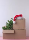 Three cardboard boxes at the top there is a red Santa Claus hat and an artificial Christmas tree Royalty Free Stock Photo