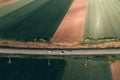 Three cars driving along the road through countryside landscape on sunny spring day, high angle view drone pov aerial shot Royalty Free Stock Photo