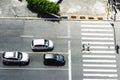 Three cars stopped and two people crossing at the crosswalk