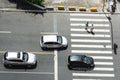 Three cars stopped and two people crossing at the crosswalk