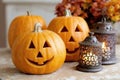 Three carved pumpkins with classic jack-o\'-lantern faces placed on a table alongside two decorative lanterns Royalty Free Stock Photo