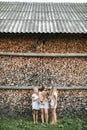 Three Caucasian cute little girls with big red cat outdoors on hot summer day, posing on the background of stacked Royalty Free Stock Photo