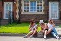 Three Caucasian women and a dog go on a trip. The girls are sitting on the curb with suitcases and waiting for a taxi Royalty Free Stock Photo