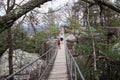 Three caucasian women and sisters walking across a swinging bridge.