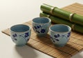 Three ceramic cups with blue interiors and floral designs are arranged on a bamboo Royalty Free Stock Photo