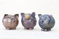 Three ceramic figurines in the form of a pig stand next to each other