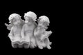 Three ceramic white angels read the book, dreaming and thinking. Royalty Free Stock Photo