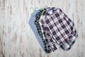 Three checkered shirts on wooden background. Fashionable concept