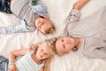 Three cheerful blonde kids are lying together on bed, looking at camera and smiling. Two boys and girl. Happy family Royalty Free Stock Photo