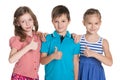 Three cheerful children hold his thumbs up