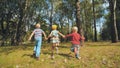 Three cheerful children are holding hands running in the park. Royalty Free Stock Photo