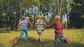 Three cheerful children are holding hands running in the park. Royalty Free Stock Photo