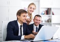 Three cheerful coworkers working in company office