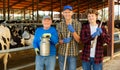 Three cheerful friendly livestock farm workers posing in cowshed