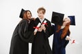 Three cheerful graduate classmates celebrating smiling rejoicing over white background. Future lawyers or medics Royalty Free Stock Photo