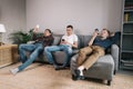Three cheerful young guys use phones on a soft couch. Royalty Free Stock Photo