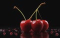 Three cherries stacked on black surface, seedless fruit from flowering plant Royalty Free Stock Photo