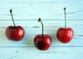 Three cherries on a white rustic wooden background Royalty Free Stock Photo