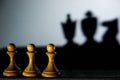 Three chess pawn casting Queen King and Knight shadow in dark concept of strength or aspirations Royalty Free Stock Photo
