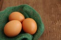 Three chicken brown eggs in a nest of green color from fabric Royalty Free Stock Photo