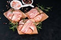 Three chicken hamburgers wrapped in bacon on cave paper with rosemary branches, black pepper and pink salt in white small plates, Royalty Free Stock Photo