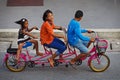 Three childred on tandem bicycle on a road