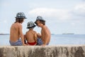 Three children, boy brothers, sitting on a concrete wall on pier on the sea, contemplating the boats Royalty Free Stock Photo