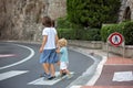 Three children, boys, brothers, holding hands and crossing a street on a striped crosswalk, checking for cars before, safety Royalty Free Stock Photo