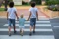 Three children, boys, brothers, holding hands and crossing a street on a striped crosswalk, checking for cars before, safety Royalty Free Stock Photo