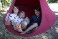 Three children, boys swinging in a big cloth swing in a park Royalty Free Stock Photo