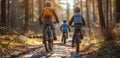 Three children cyclists in helmets ride on a sunlit forest path, surrounded by tall trees and spring foliage. Royalty Free Stock Photo