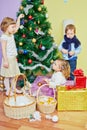 Three children decorate christmas tree, girl hangs Royalty Free Stock Photo