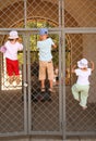 Three children hang on grill of gate