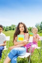 Three children hold notebooks and sit on chairs Royalty Free Stock Photo