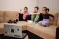 Three children with kitten sitting on the living room watching movie or cartoon from laptop Royalty Free Stock Photo