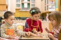 Three children make dough cookies.