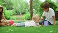 Three children playing with toys in park. Toddler lying on green grass outside Royalty Free Stock Photo